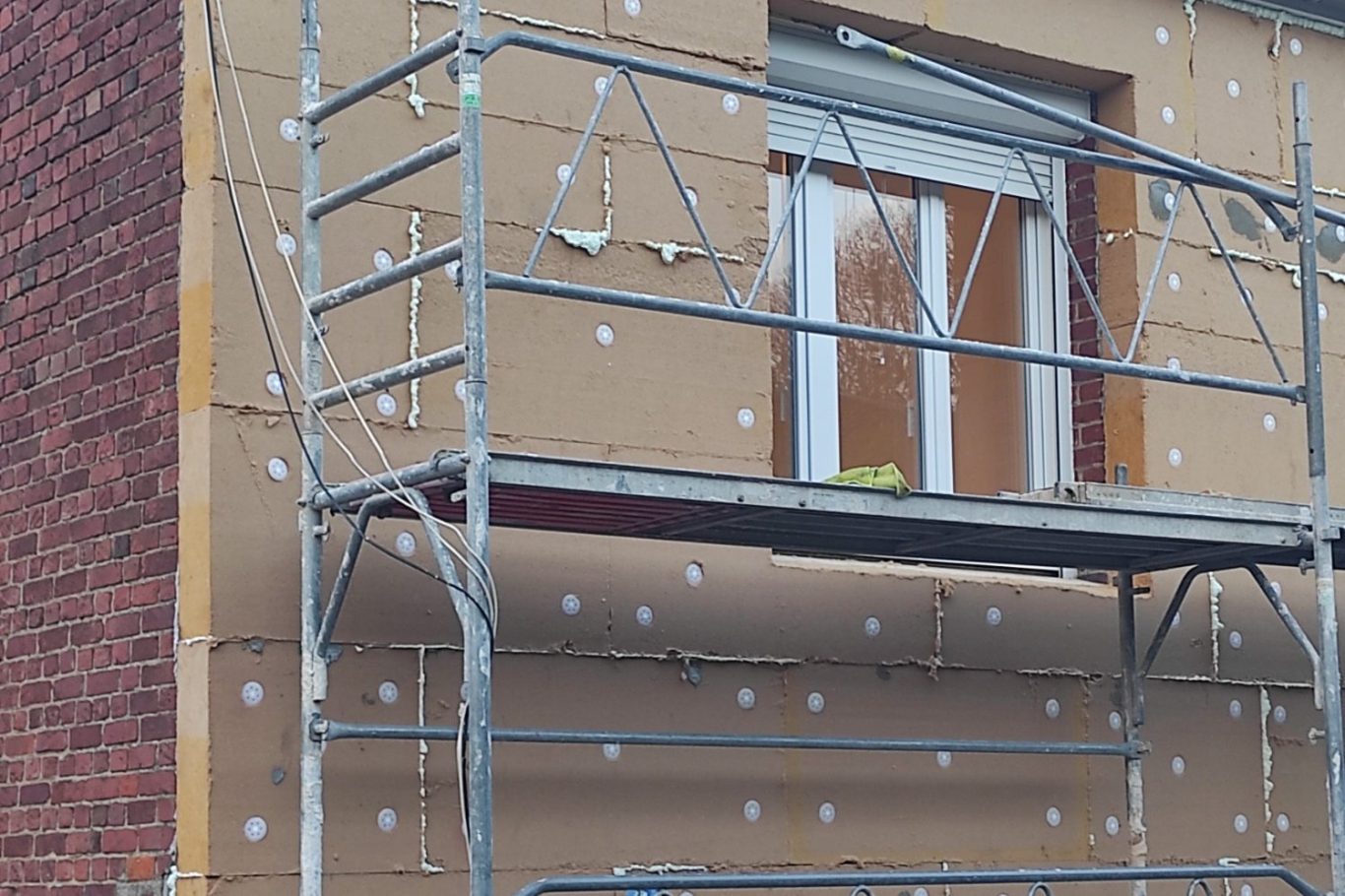 Pose d'enduit projeté façadier qui pose un enduit projeté sur une façade ou un pignon de maison